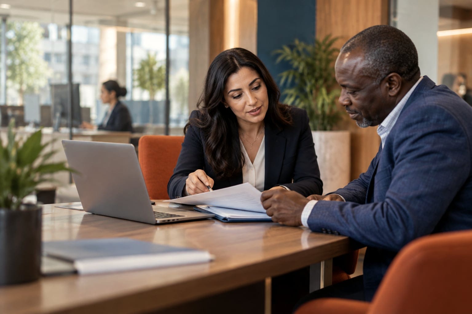 A credit officer and a business owner going through an application folder together at a desk.